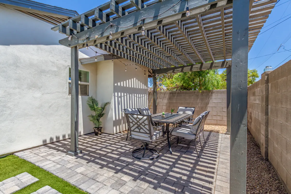 A welcoming pergola with a large outdoor dining table and chairs, flanked by potted plants. The setting is ideal for sunset dinners, morning coffees, and outdoor celebrations, blending nature with comfort.