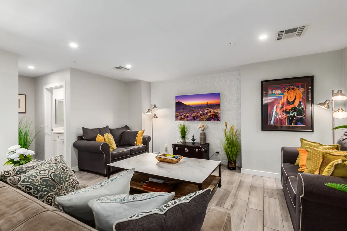 A cozy living room scene with a sofa adorned with decorative pillows facing a television, a well-styled coffee table, and wall art, capturing the essence of movie nights and shared moments.