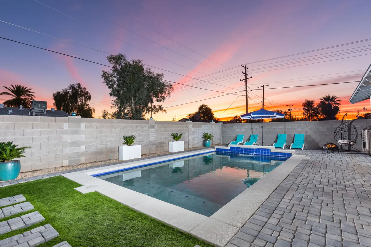 A tranquil swimming pool scene at sunset, with lounge chairs and a glowing sky, perfect for evening swims or starlit gatherings by the water.
